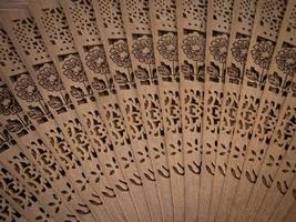 Close-up photo of a hand fan made of wood with flower carvings