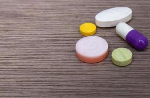 Close-up photo of various medicines and supplements isolated on the background on a wooden board