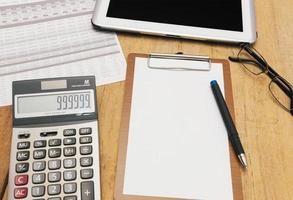 The top view of the office desk blank paper, pen, calculator, tablet. Financial planning and work concept. photo