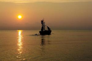 Silhouette of two people on a fishing boat that is about to go fishing in the morning sun.copy space. photo