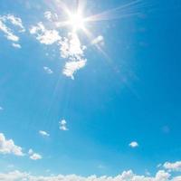 Natural abstract background of bright blue sky and fluffy white clouds on a sunny, light a flare and sun. photo