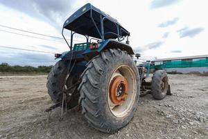 tractor azul estacionado en un claro en preparación para la capa superior del suelo y un hermoso cielo azul en el fondo. el concepto de una excavadora prepara la capa superior del suelo para la construcción. foto