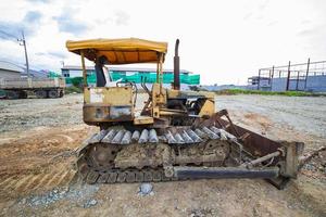 Bulldozer sobre orugas amarillo estacionado en un claro en preparación para la capa superior del suelo y un hermoso cielo azul en el fondo. el concepto de una excavadora prepara la capa superior del suelo para la construcción. foto