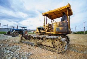 Bulldozer sobre orugas amarillo estacionado en un claro en preparación para la capa superior del suelo y un hermoso cielo azul en el fondo. el concepto de una excavadora prepara la capa superior del suelo para la construcción. foto