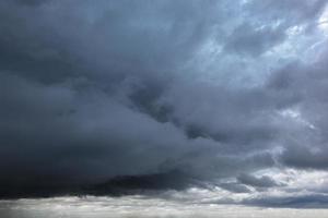 The dark sky with heavy clouds converging and a violent storm before the rain.Bad weather sky. photo