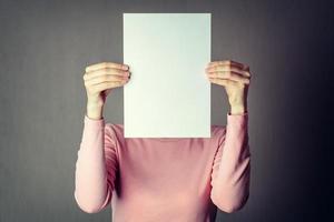 anonymous woman covering face with white paper sheet photo