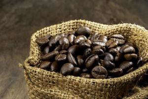 Coffee beans in a coffee burlap bag on a wooden surface.shallow focus effect. soft focus. photo