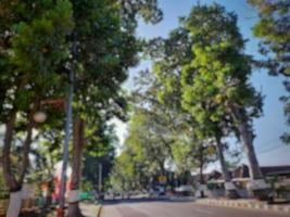 Defocused abstract background of road view with green trees on the left and right photo