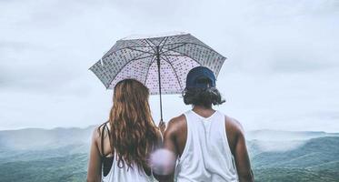 Lover women and men asians travel relax in the holiday. stood in rain umbrellas on the mountain. During the rainy season.Thailand photo
