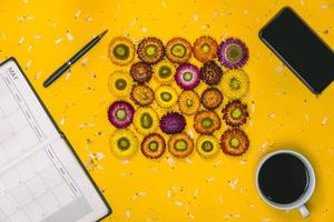 Top view concept of pastel yellow background, Colorful flowers that are arranged in a rectangular shape with a notebook, pen and Cup of coffee placed, Mobile phone. concept, note, nature, book. photo