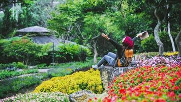 mujer viaje naturaleza en el jardín de flores. relájese sentado en las rocas y leyendo libros en medio de la naturaleza en el parque nacional doi inthanon. foto