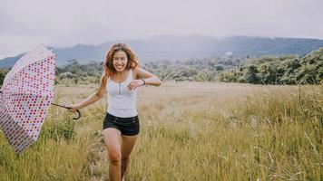 Asian women travel relax in the holiday. Running umbrella sunshine on a green pasture. photo