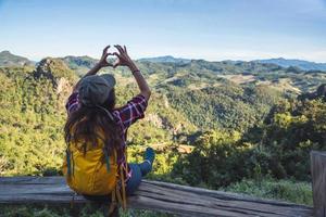 Young woman Tourists with backpacks Happy to travel She raised her hand to make a heart shape and enjoy the natural scenery on the mountain. photo