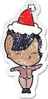 distressed sticker cartoon of a squinting girl wearing santa hat vector