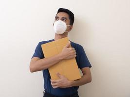 hombre con mascarilla quirúrgica con caja de cartón sobre fondo blanco foto