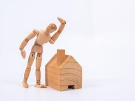 Man leaned against the model of a house isolated on white background. Concept with a wooden puppet photo