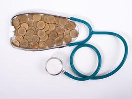 Medical stethoscope and coins stack isolated on white background. Medical insurance concept. photo