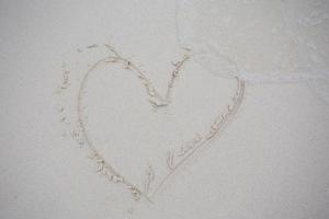 corazones dibujados en la arena de una playa foto