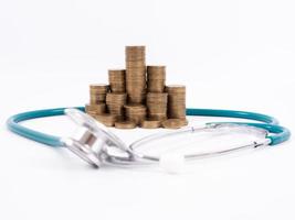 Medical stethoscope and coins stack isolated on white background. Medical insurance concept. photo