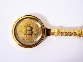 Golden bitcoin magnifying glass on a blurred background of coins photo