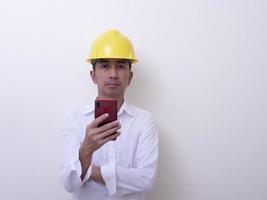 engineer with hands crossed wearing yellow helmet on white background photo