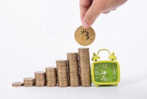 Hand Holding Bitcoin and many coin and clock for saving money concept on white background photo