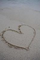 corazones dibujados en la arena de una playa foto