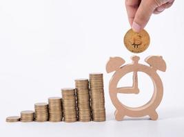 Hand Holding Bitcoin and many coin and clock for saving money concept on white background photo