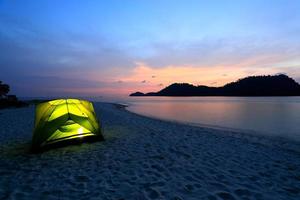 green tent on beach in sunset photo