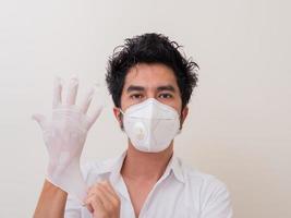 Confident man surgeon in medical mask on face wearing protective sterile glove on hand photo