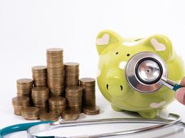 Medical insurance concept. Piggy bank, medical stethoscope and hand with coin photo