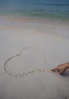 corazones dibujados en la arena de una playa foto