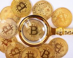 Golden bitcoin magnifying glass on a blurred background of coins photo