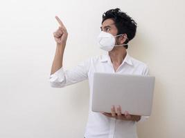 Business man in medical face mask works on laptop at home photo