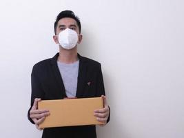 Happy delivery service employee in medical face mask carry cardboard box in hand photo