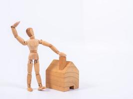 Man leaned against the model of a house isolated on white background. Concept with a wooden puppet photo