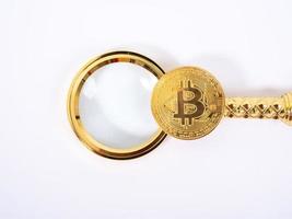 Golden Bitcoin replica and magnifying glass on white   background.Business and finance concept. photo