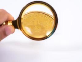 Golden bitcoin magnifying glass on a blurred background of coins photo