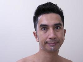 los hombres asiáticos se lavan la cara con espuma, el concepto de cuidado de la piel de los hombres foto