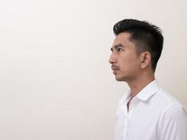 joven asiático aislado de fondo blanco mirando hacia los lados foto