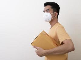 Happy delivery service employee in medical face mask carry cardboard box in hand photo