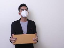 Happy delivery service employee in medical face mask carry cardboard box in hand photo