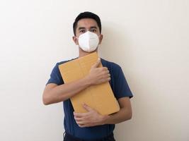 hombre con mascarilla quirúrgica con caja de cartón sobre fondo blanco foto