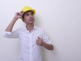 engineer with hands crossed wearing yellow helmet on white background photo