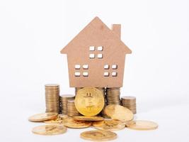 compra y venta de bienes raíces por concepto de bitcoins con una pequeña casa de campo y una moneda de metal dorado. foto