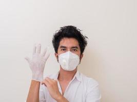 Confident man surgeon in medical mask on face wearing protective sterile glove on hand photo