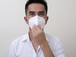 Asian young man in white shirt and medical mask to protect COVID-19 photo