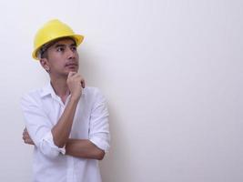 engineer with hands crossed wearing yellow helmet on white background photo