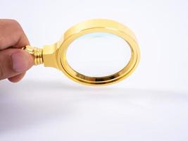 Golden magnifying glass in hand on white background photo
