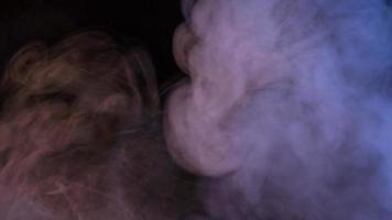 Conceptual image of multi-colored smoke isolated on dark black background and wooden table. photo